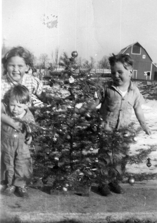 1942 ? Doris, Charles and A. B. Fisher with Christmas tree.  Bob Sullivan’s barn in back ground