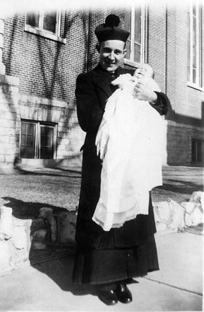 Priest holding baby following baptism